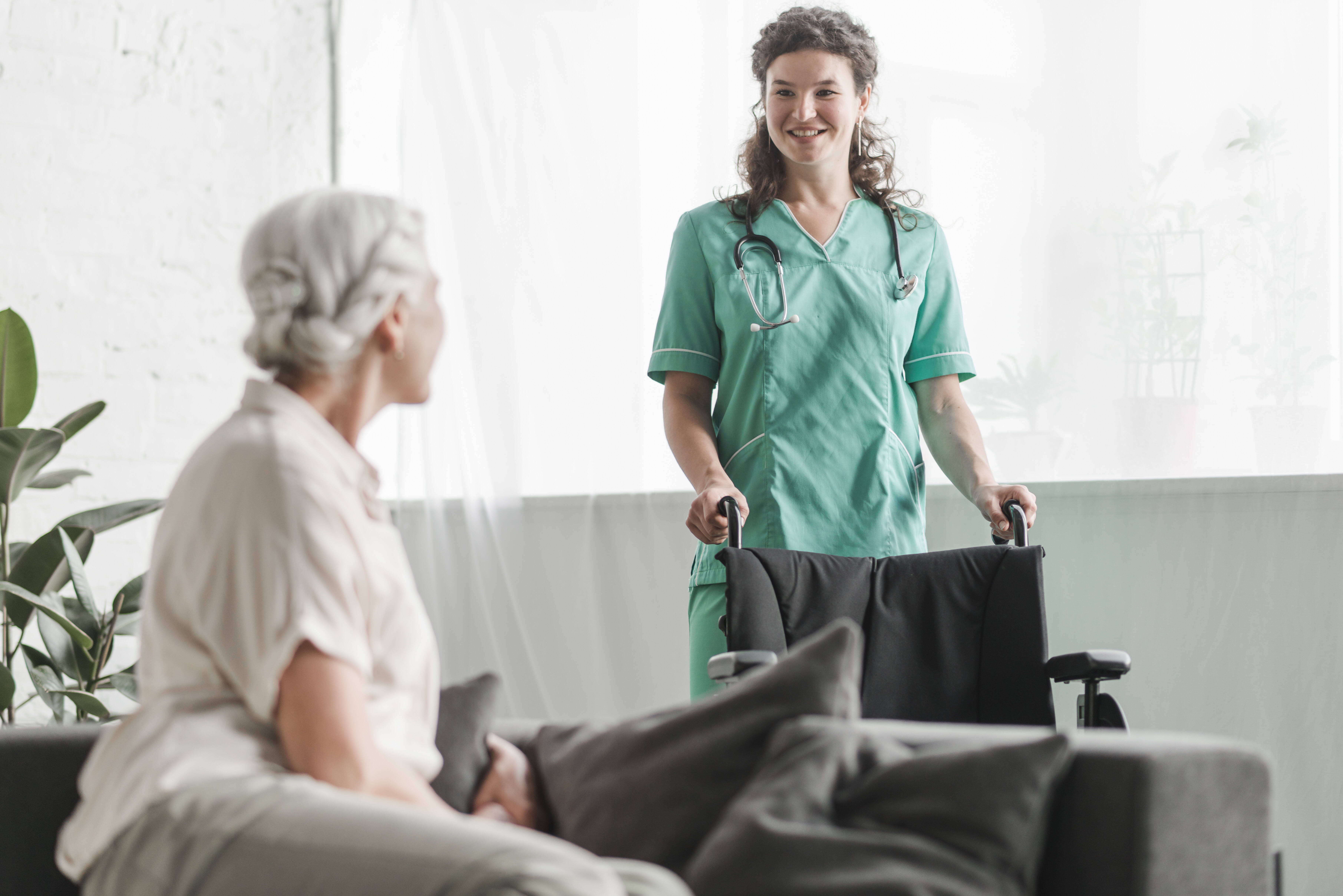 senior-woman-looking-at-smiling-female-nurse-with-wheelchair.jpg