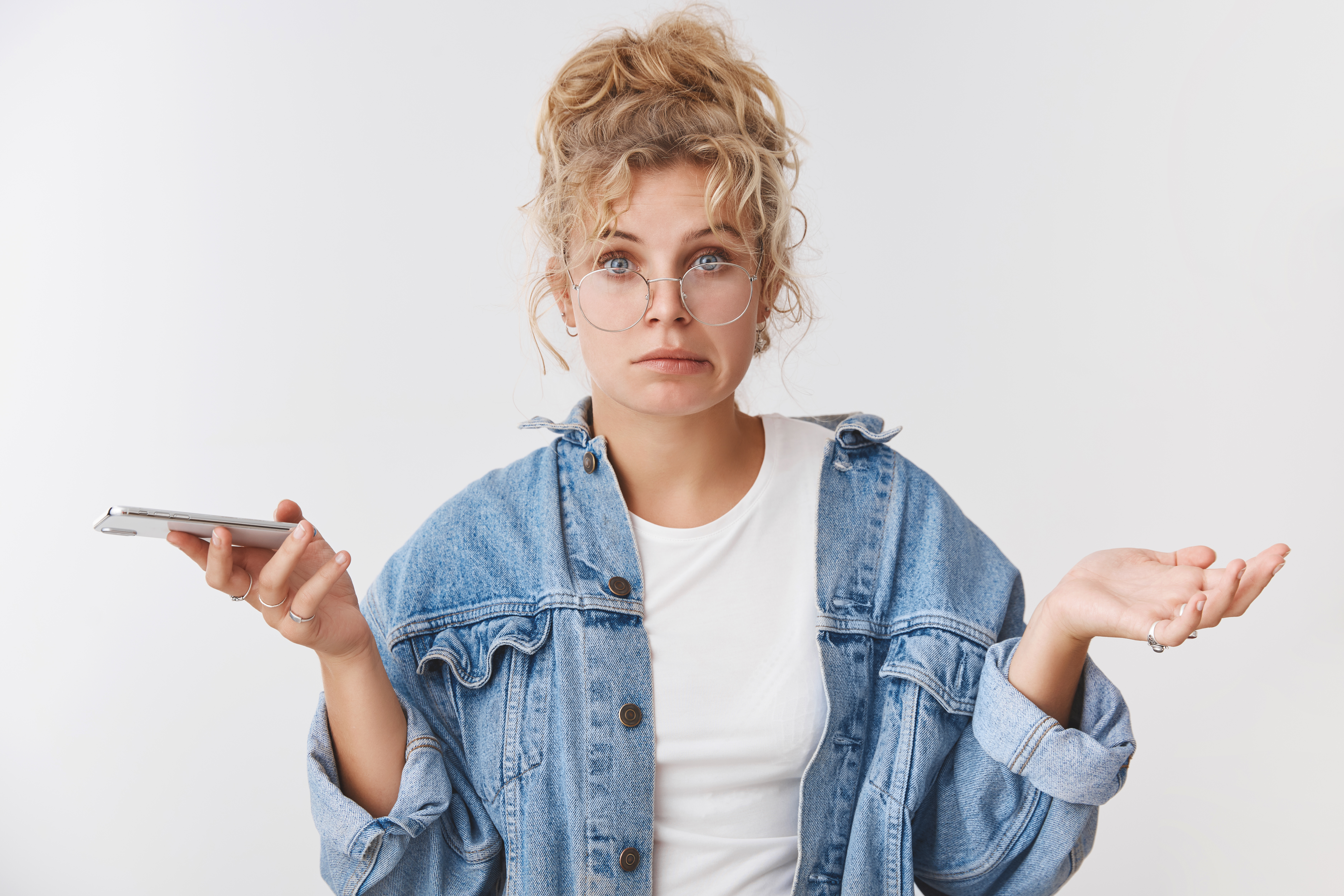 maladroit-incertain-desempare-mignon-maladroit-europeenne-blonde-assistante-porter-des-lunettes-chignon-desordonne-souriant-incertain-ecarter-les-mains-sur-le-cote-inconscient-tenant-un-smartphone-pas-sur-de-sa.jpg